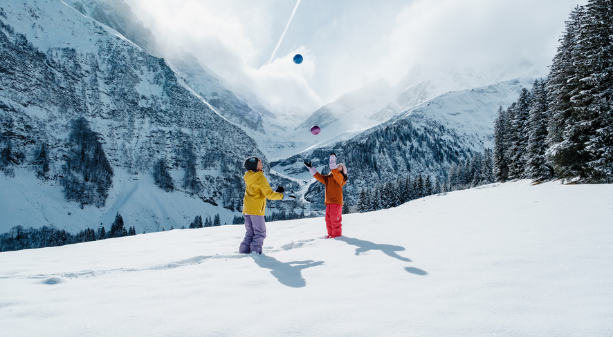 Kinder spielen im Tiefschnee mit bunten Bällen