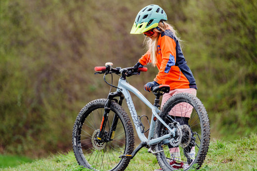 Velotouren mit Kindern - Kind steht mit Fahrrad auf Wiese