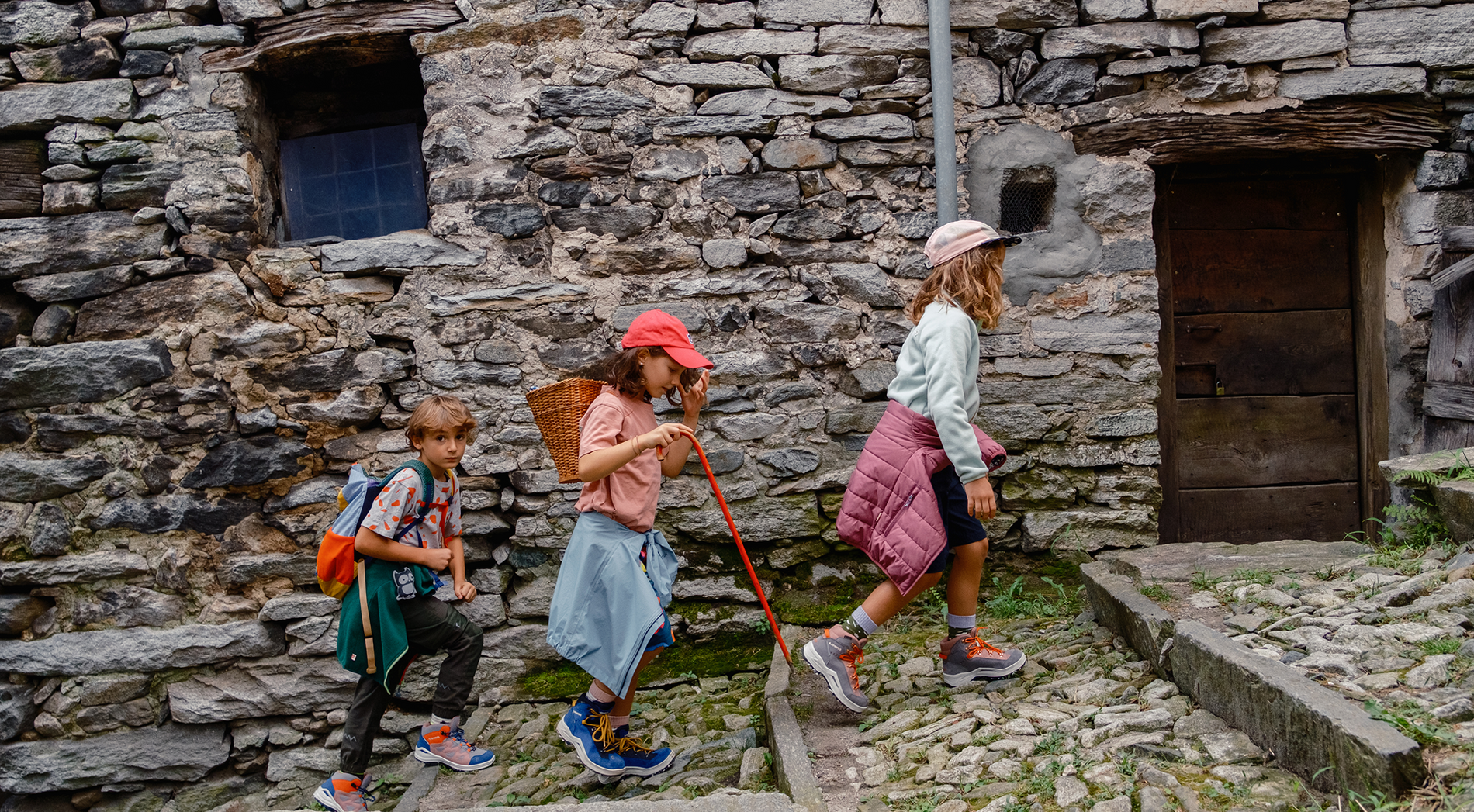Drei Kindern wandern zusammen durch ein Steindorf
