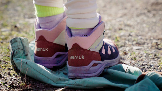 Kind steht mit Wanderschuhen auf namuk Hose