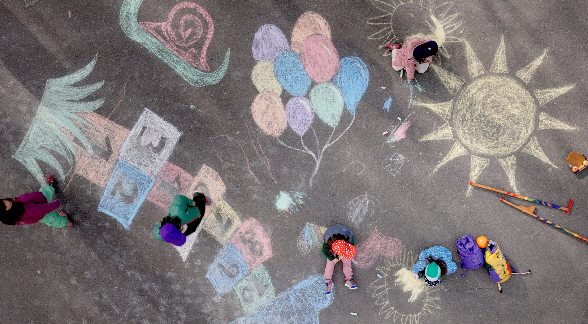 Kinder spielen auf einem mit bunter Kreide bemaltem Spielplatz
