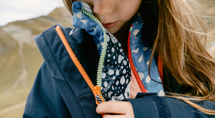 Ein Kind zieht seine Zip-in Jacke an